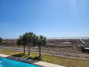 Una piscina con vistas a una playa y una valla blanca.