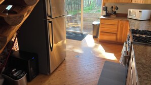 Een moderne keuken met houten kastjes, een roestvrijstalen koelkast, een magnetron en een gasfornuis.