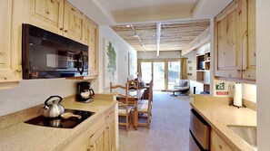 A compact kitchen with wooden cabinets, a built-in microwave, a kettle, and a coffee maker.