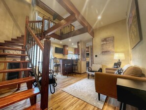 A spacious living area with a wooden staircase, a kitchen, and a dining area.
