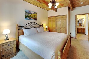 A bedroom with a bed, nightstands, a painting, a wardrobe, and a bathroom visible through an open door.