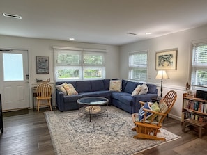 A living room with a sectional sofa, a coffee table, a rocking chair, a bookshelf, and a rug. - Sutton Place: Large yard perfect for outdoor activities. (Ocracoke)
