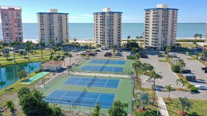 Un hôtel situé en bord de mer, composé de plusieurs immeubles de grande hauteur, doté d’un terrain de tennis et d’un parking.