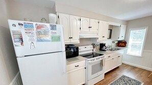 Una cucina con mobili bianchi, un frigorifero, un piano cottura e un forno a microonde.