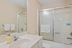 Ein Badezimmer mit Waschbecken, Spiegel, Dusche und Toilette.