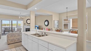 A kitchen with a large island, a dining area with chairs, and a view of the outdoors.