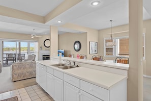 A kitchen with a large island, a dining area with chairs, and a view of the outdoors.