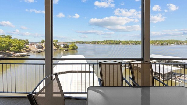 A covered outdoor seating area with a view of a lake and distant shoreline.