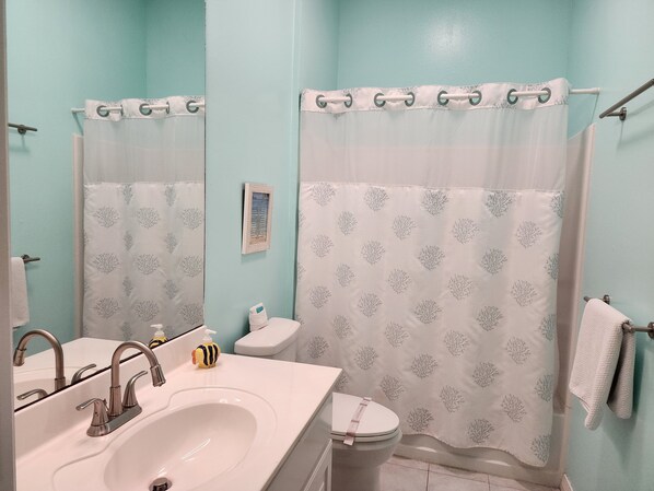 Un baño con lavamanos, inodoro y cortina de ducha.