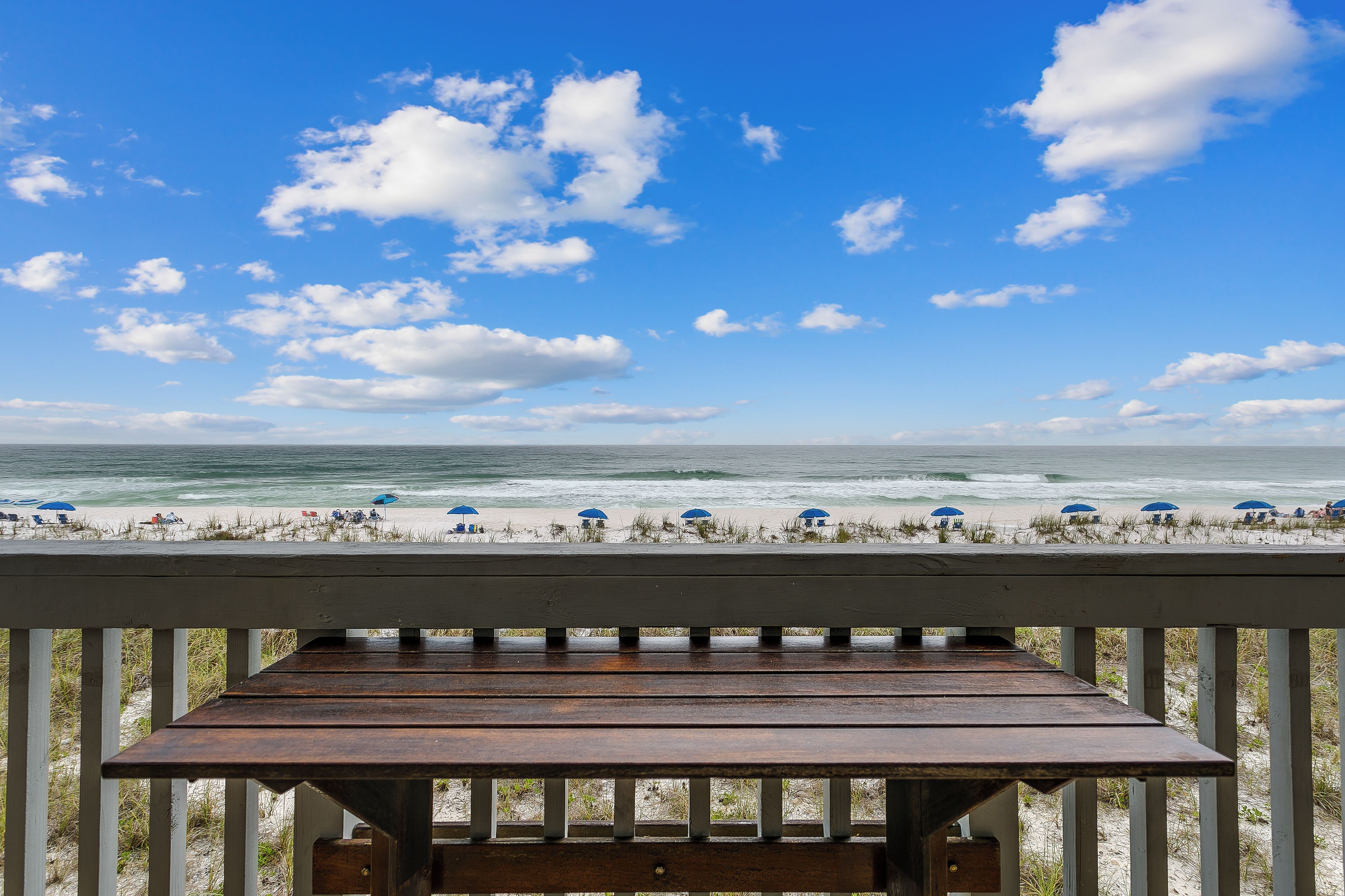 A wooden deck with a view of the beach and ocean.