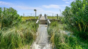 A wooden bridge leading to a building with a metal railing. - 🏖️Beautiful 2 BR / 2BTH Beachfront Condo with Community Swimming Pool! (Pensacola Beach)