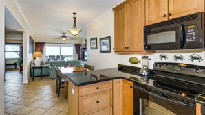 A kitchen with wooden cabinets, a black microwave, and a stove. - 🏖️Beautiful 2 BR / 2BTH Beachfront Condo with Community Swimming Pool! (Pensacola Beach)
