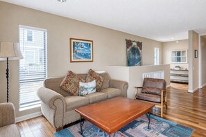 A living room with a sofa, armchair, coffee table, and a painting on the wall.