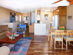 Relax in this open-plan living space featuring a sofa, coffee table, and dining area with a refrigerator and sink.