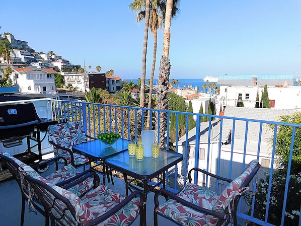 Enjoy a meal on the balcony with a view of the coastal area and surrounding buildings.
