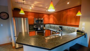 A modern kitchen with wooden cabinets, stainless steel appliances, and a granite countertop.