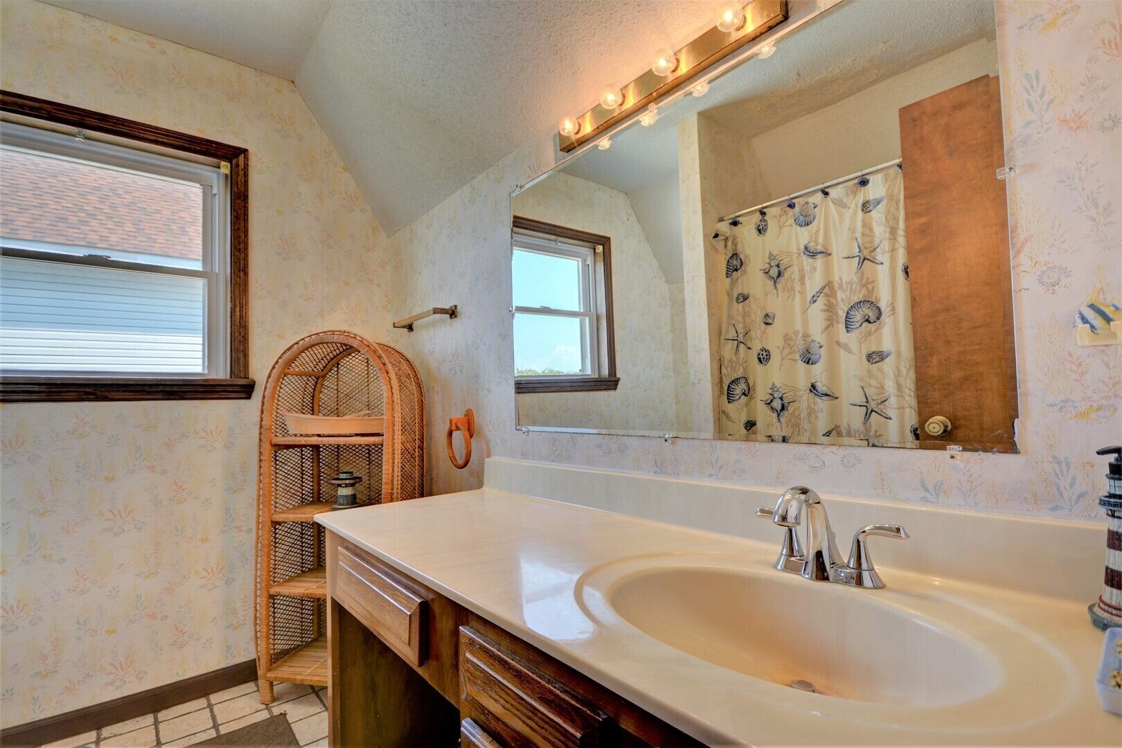 A bathroom with a large sink, vanity, and a mirror with lights.
