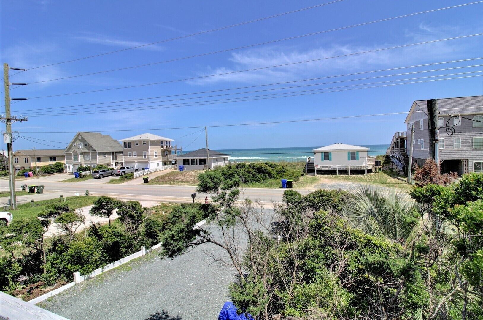 A coastal residential area with houses, a road, and a beach in the background.