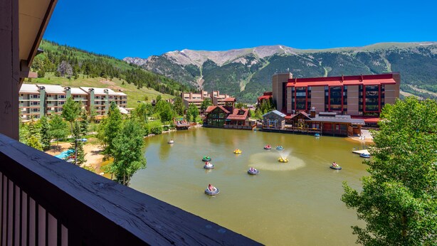 A view of a resort area with a lake, paddle boats, and buildings with red roofs.