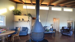 Un ampli saló amb una llar de foc gran, terres de fusta i una zona d'estar acollidora amb un sofà i cadires.