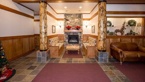 A lobby with a stone fireplace, wooden columns, and a Christmas tree. - Updated, Comfortable Condo with Valley Views (Whitefish)
