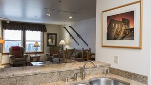 A kitchen with granite countertops, a double sink, and a dining area with a table and chairs. - Updated, Comfortable Condo with Valley Views (Whitefish)