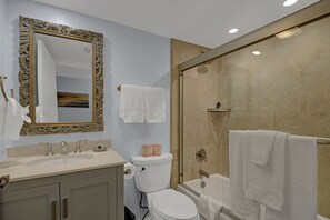 A bathroom with a large ornate mirror, a sink, a toilet, and a shower area. - A20: Remodeled 2 BD Condo with POOL (Avalon)