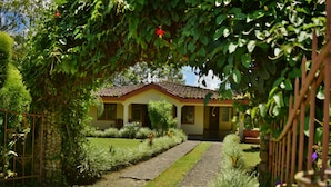Uma casa com telhado de cerâmica, rodeada por um jardim bem cuidado e um caminho de pedra que leva à entrada.