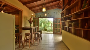 Cozinha com banquetas de madeira, piso de azulejos e vista para o verde lá fora.