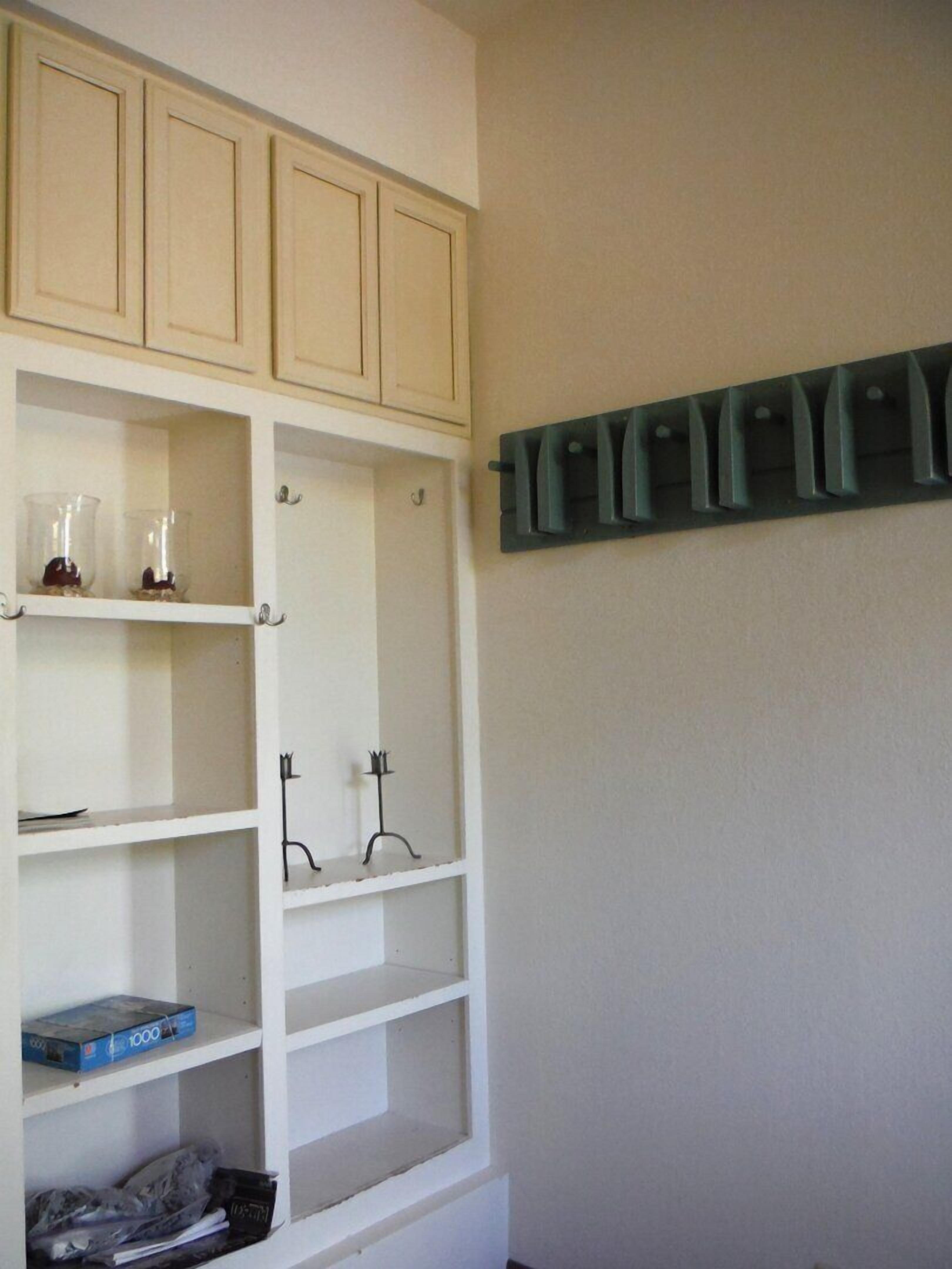 Een kamer met witte kasten, een blauwe doos op het onderste plankje en een groen wandrek.