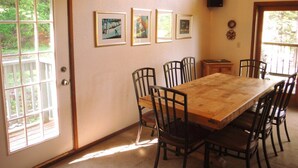 A dining area with a wooden table and chairs, framed pictures on the wall, and a speaker. - Comfortable & Spacious Ski-In/Ski-Out Cabin (Whitefish)