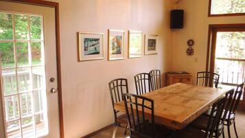 A dining area with a wooden table and chairs, framed pictures on the wall, and a speaker.