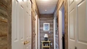 A hallway with wooden walls, white doors, and a small table with a lamp. - Hangin' Loose:  Pet friendly, deck, screened porch, ramp (Ocracoke)
