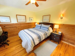 Une chambre à coucher comprenant un lit, une tête de lit en bois, des tables de chevet, un bureau et une chaise.