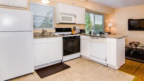 A compact kitchen with white cabinets, a microwave, stove, oven, and a coffee maker. - Royal Palm Unit 4 4 1,000 sq ft of FUN (Clearwater Beach)