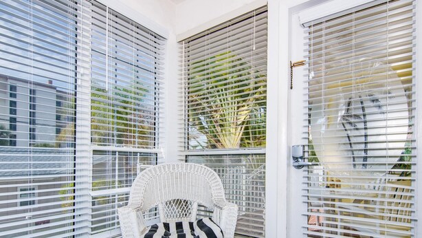 A corner room with a white wicker chair, a blue and white striped pillow, and a blue rug. - Royal Palm Unit 4 4 1,000 sq ft of FUN (Clearwater Beach)