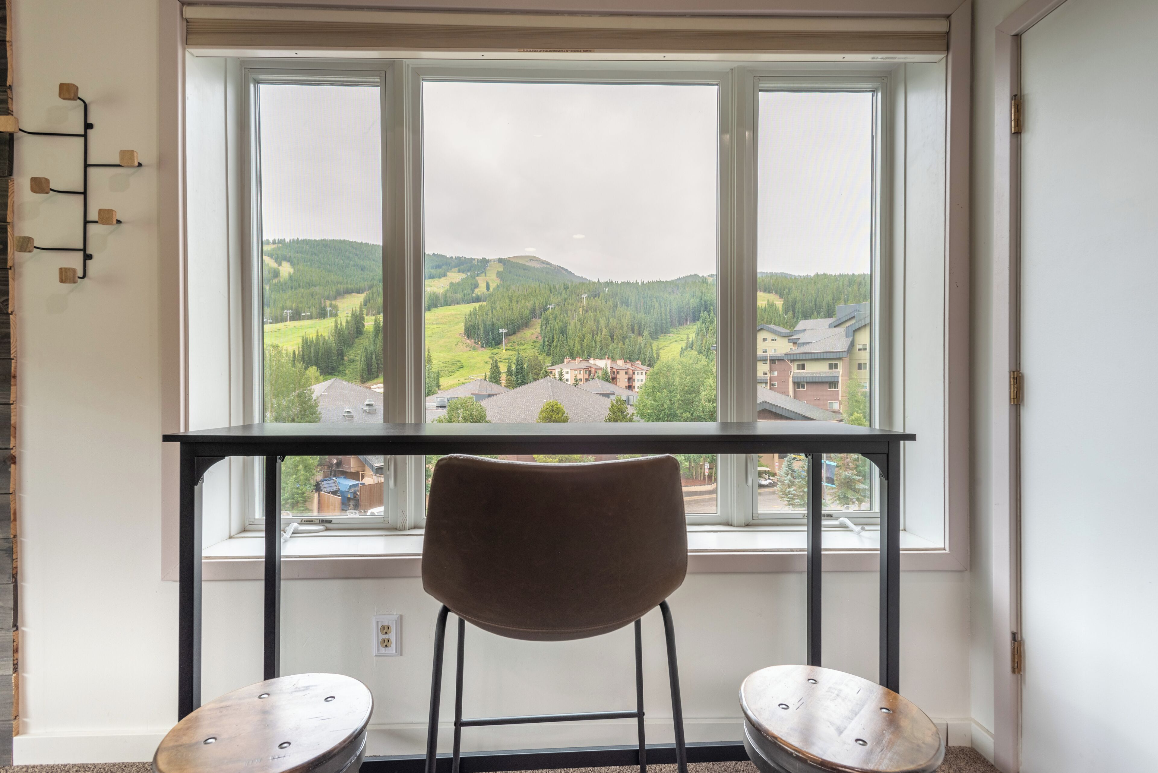 Une pièce avec une grande fenêtre, un fauteuil marron et une petite table.