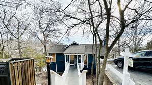 Une maison à deux étages avec un porche, une clôture en bois et une allée.