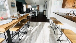 Un vaste espace de vie comprenant un coin repas avec une table et des bancs en bois, une cuisine avec des meubles en bois et une vue sur la salle à manger.