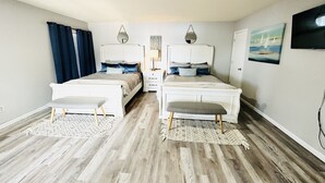 Une chambre double avec deux lits, une table de chevet, une lampe et un tableau au mur.