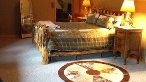 Een slaapkamer met een houten bed, een spiegel, een nachtkastje met een lamp en een vloerkleed met een rond ontwerp.