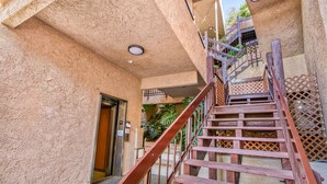 A staircase leading to an upper level with a textured wall and a metal railing. - A23 - Bahia Vista Condo: 2 Bedroom, 1.75 Bath, Pool (Avalon)
