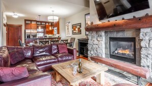 Ein gemütliches Wohnzimmer mit Kamin aus Stein, Ledersofa und Couchtisch aus Holz.
