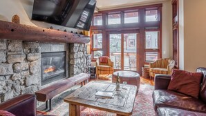 Ein gemütliches Wohnzimmer mit Kamin aus Stein, einer hölzernen Bank und einem Ledersofa.