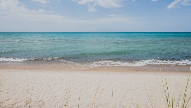 A beach with clear turquoise water and a sandy shore. - Union Pier Condo with Association Heated Pool. Close to Beach And Downtown! (Union Pier)