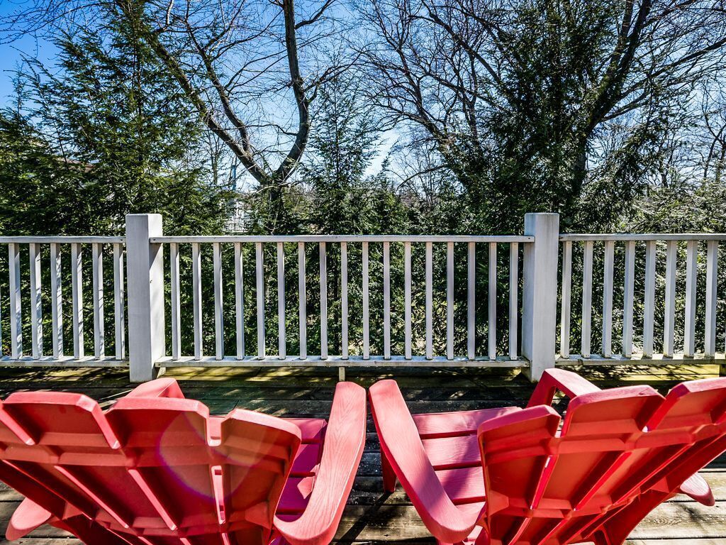 A deck with red chairs and a white fence.
