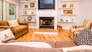 A living room with a fireplace, a flat-screen TV, and two sofas. - Union Pier Condo with Association Heated Pool. Close to Beach And Downtown! (Union Pier)