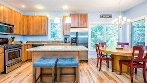 A modern kitchen with wooden cabinets, stainless steel appliances, and a central island with bar stools. - Union Pier Condo with Association Heated Pool. Close to Beach And Downtown! (Union Pier)