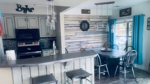 Een keuken met een bar, houten wanddecoratie en een eettafel met stoelen.