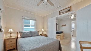 A bedroom with a bed, nightstands, a ceiling fan, a window, and a dresser. - 331D: Quaint Cottage, 3 Blocks from Beach + Open Living Space + Sleeps 8 Tandem (Avalon)